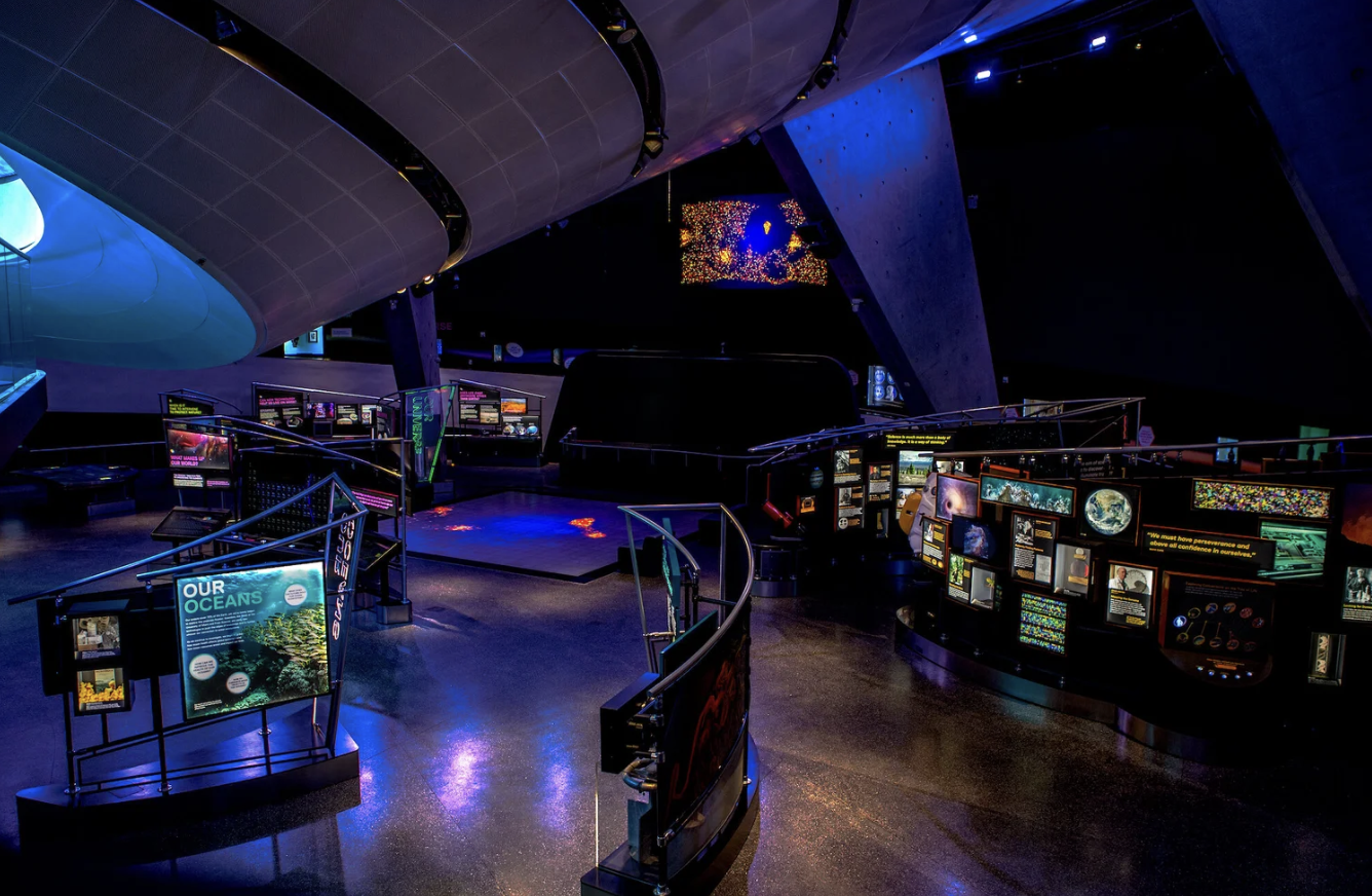 Gallery interior at the Frost Museum of Science, lit by exhibit screens